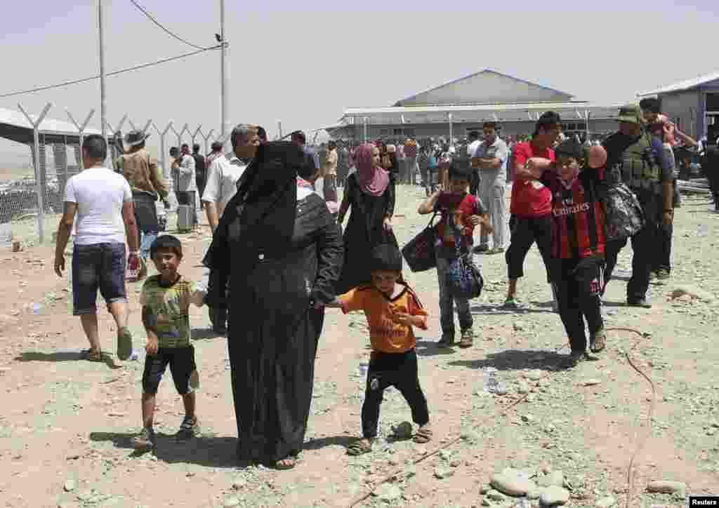 Para keluarga yang melarikan diri dari kekerasan di Mosul menunggu di pos pemeriksaan di luar kota Irbil, Irak (10/6).