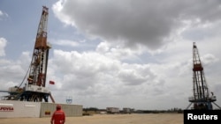 Un trabajador de un campo petrolífero camina junto a las plataformas de perforacion en un pozo de petróleo operado por la petrolera estatal de Venezuela PDVSA. Abril 16, 2015. Foto: Reuters.