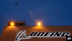 ARCHIVO - Un avión vuela por encima de un letrero en el centro de entrega de Boeing 737, el 19 de octubre de 2015, en el Campo Boeing, en Seattle.