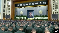In this image taken from video footage run by China's CCTV, attendees bow during a formal memorial for the late former Chinese President Jiang Zemin held at the Great Hall of the People in Beijing on Dec. 6, 2022. Words at top reads "Comrade Jiang Zemin Memorial Service" 