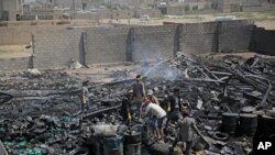 FILE - Workers salvage oil canisters from the wreckage of a vehicle oil store hit by Saudi-led airstrikes in Sanaa, Yemen, July 2, 2020.