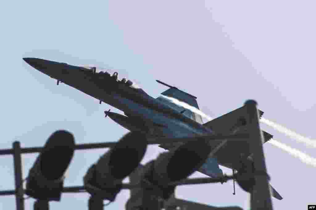 This U.S. Navy photo obtained Sept. 24, 2014 shows an F/A-18F Super Hornet attached to the Fighting Black Lions of Strike Fighter Squadron (VFA) 213 as it flies over the aircraft carrier USS George H.W. Bush, in the Arabia Gulf.