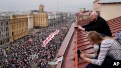 Sejumlah orang di atap mengabadikan demo oleh pendukung oposisi yang sedang menuju Independence Square di Minsk, Belarusia, 23 Agustus 2020.