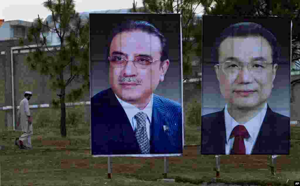 A man walks next to huge portraits of Chinese Premier Li Keqiang, right, and Pakistani President Asif Ali Zardari, left, displayed near the presidency in Islamabad, Pakistan.
