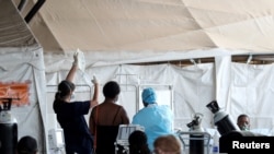 Health workers attend to patients in tents at the parking lot of the Steve Biko Academic Hospital, amid a nationwide coronavirus disease (COVID-19) lockdown, in Pretoria, South Africa, Jan. 11, 2021.