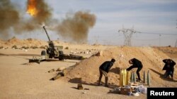 FILE - Libya Dawn fighters fire an artillery cannon at Islamic State militants near Sirte.