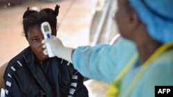 Une jeune fille soupçonnée d'être infectée par le virus Ebola fait prendre sa température dans un hôpital de Kenema, en Guinée, le 16 août 2014.