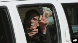 EgyptAir plane hijacking suspect Seif Eddin Mustafa flashes the victory sign as he leaves a court in a police car after a remand hearing as authorities investigate him on charges including hijacking, illegal possession of explosives and abduction in the Cypriot coastal town of Larnaca Wednesday, March 30, 2016. 