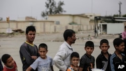 FILE - In this May 2, 2017 file photo, Mosul residents wait in a queue for food distribution in western Mosul, Iraq. 
