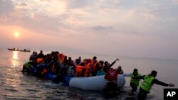 FILE - Volunteers help migrants and refugees on a dingy as they arrive at the shore of the northeastern Greek island of Lesbos, after crossing the Aegean sea from Turkey, March 20, 2016. 