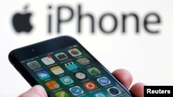 FILE - An Apple iPhone 7 and the company logo are seen in this picture taken, Feb. 1, 2017.