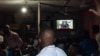 Des Congolais regardent la télévision pendant que le Président Félix Tshisekedi prononce son discours à Kinshasa, le 6 décembre 2020.
