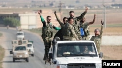 Turkey-backed Syrian rebel fighters gesture as they ride on a vehicle near the border town of Tal Abyad, Syria, Oct. 22, 2019.
