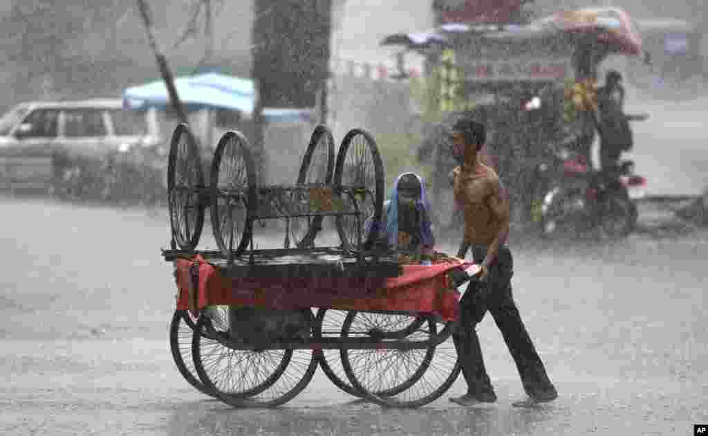 បុរសម្នាក់រុញរទេះមួយកណ្តាលភ្លៀងដ៏ខ្លាំងក្នុងទីក្រុង Jammu ប្រទេសឥណ្ឌា។