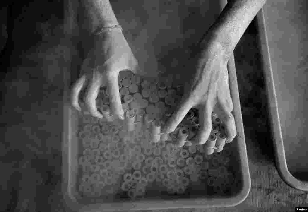 A worker removes paper rolls after filling them with a gunpowder mixture to make firecrackers, at a factory on the outskirts of Ahmedabad, India.
