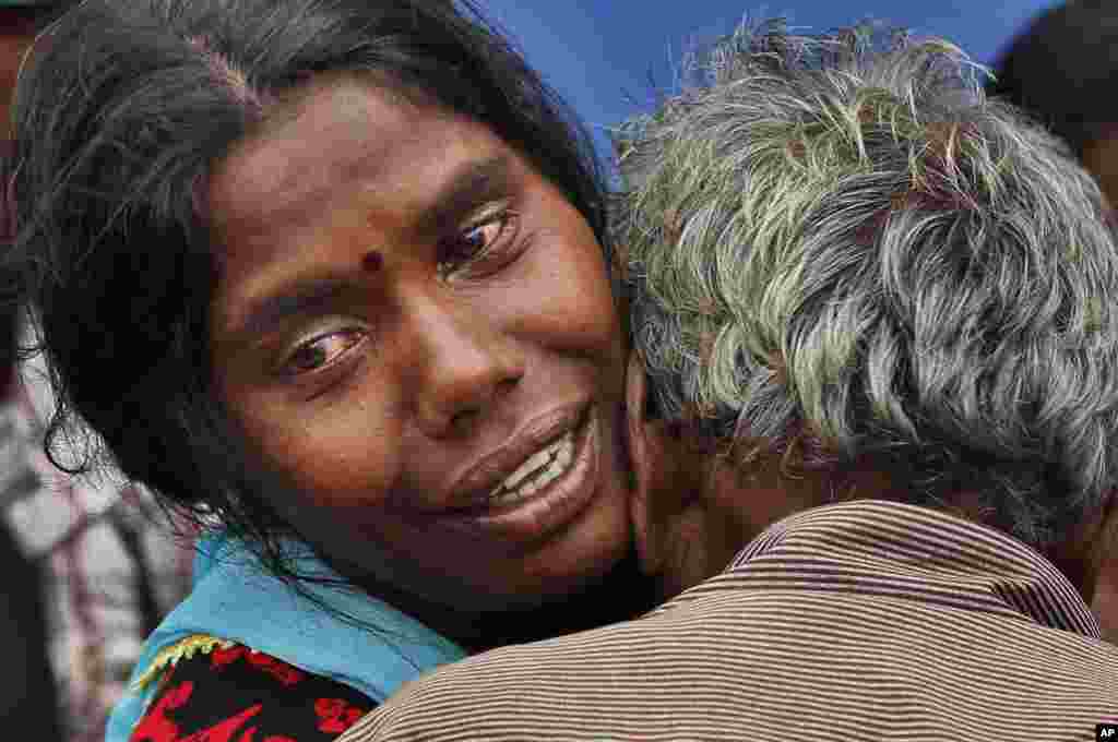 A Sri Lankan mudslide survivor who lost her two daughters is comforted by her father as she cries at a relief center set up in a school in Punagala in Badulla district, about 220 kilometers east of Colombo, Sri Lanka, Oct.30, 2014.