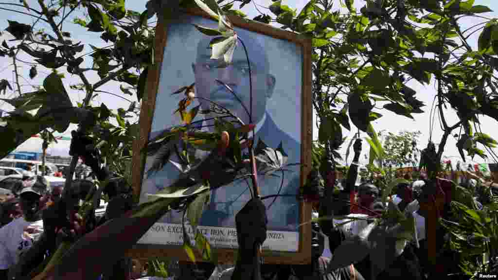 Des partisans du président Pierre Nkurunziza tiennent son effugie et des branches d'arbre, à l'annonce de son retour au palais présidentiel à Bujumbura, Burundi, vendredi 15 mai 2015.