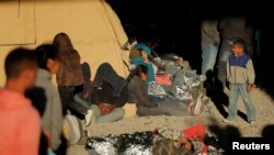 Seorang remaja berjalan dekat para migran yang beristirahat di sebuah tempat penampungan di El Paso, Texas, 29 Maret 2019. Para migran itu ditahan oleh Dinas Bea Cukai dan Perlindungan Perbatasan AS setelah ketahuan menyeberang perbatasan AS-Meksiko secara illegal.