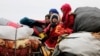 FILE - Syrians from western Aleppo countryside ride with belongings in Hazano near Idlib, Syria, Feb. 11, 2020.