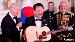 El presidente de Estados Unidos, Joe Biden, presenta una guitarra firmada por el artista Don McLean al presidente de Corea del Sur, Yoon Suk Yeol, en una cena oficial de Estado, durante la visita del presidente de Corea del Sur, Yoon Suk Yeol, en la Casa Blanca en Washington, el 26 de abril de 2023. REUTERS/Evelyn Hockstein