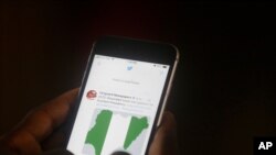 FILE - A man uses his mobile phone to read news on Twitter inside an office in Lagos, Nigeria, June 7, 2021.