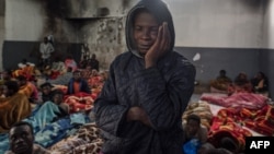 FILE - A migrant holds his head as he stands in a packed room at the Tariq Al-Matar detention center on the outskirts of the Libyan capital Tripoli, Nov. 27, 2017.