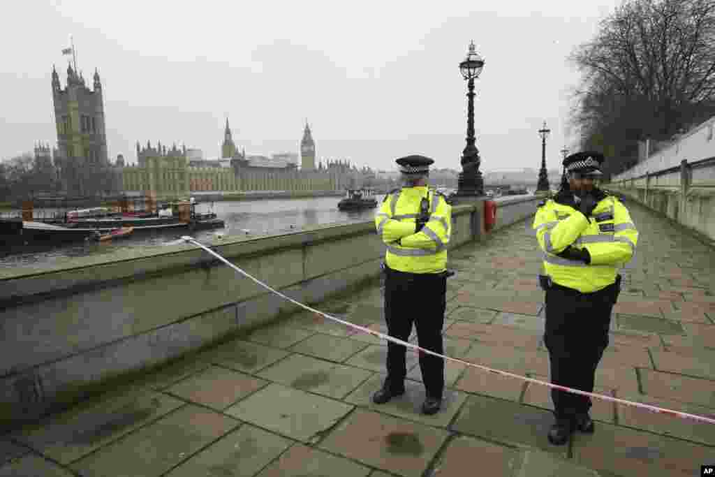 Police guard a cordon on the embankment with Britain's Houses of Parliament, left, in London, March 23, 2017, after attacks in London Wednesday.
