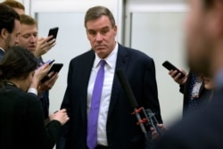 FILE - Sen. Mark Warner, D-Va., talks to reporters as he walks to attend the impeachment trial of President Donald Trump, Jan. 28, 2020, on Capitol Hill in Washington.