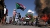 People chant slogans and burn tires during a protest to denounce the October 2021 military coup, in Khartoum, Sudan, Tuesday, Jan. 4, 2022.