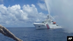FILE - Chinese Coast Guard members approach Filipino fishermen as they confront each other off Scarborough Shoal in the South China Sea, also called the West Philippine Sea, Sept. 23, 2015.