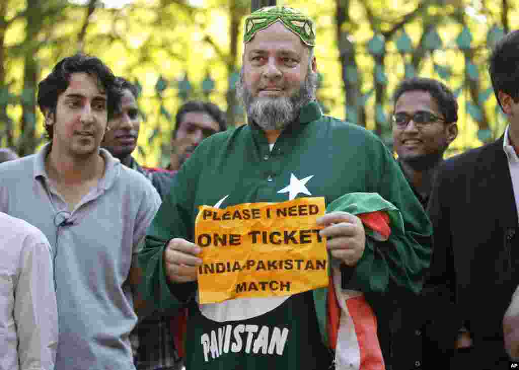 A Pakistan cricket fan, Mohammad Bashir, center, of Chicago, holds a paper which reads 'Please I need one ticket India Pakistan match' as he stands in front of the Chinnaswamy Stadium in Bangalore, India, December 24, 2012.