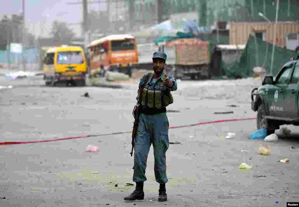 An Afghan police officer keeps watch at the site of bomb blasts in Kabul, June 6, 2014.