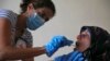 FILE - A member of the International Red Cross takes a saliva sample from a woman whose sister went missing in 1976 during the Lebanese civil war, at her home, in a southern suburb of Beirut, Lebanon, July 11, 2016.
