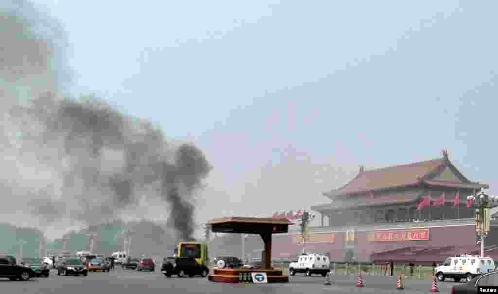 Vehicles travel along Chang'an Avenue as smoke raises in front of a portrait of late Chinese Chairman Mao Zedong at Tiananmen Square in Beijing.