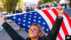 Kelly Janowiak of Chicago, prays with a conservative Christian Evangelical group while holding a American flag, Nov. 2, 2020, in Washington.