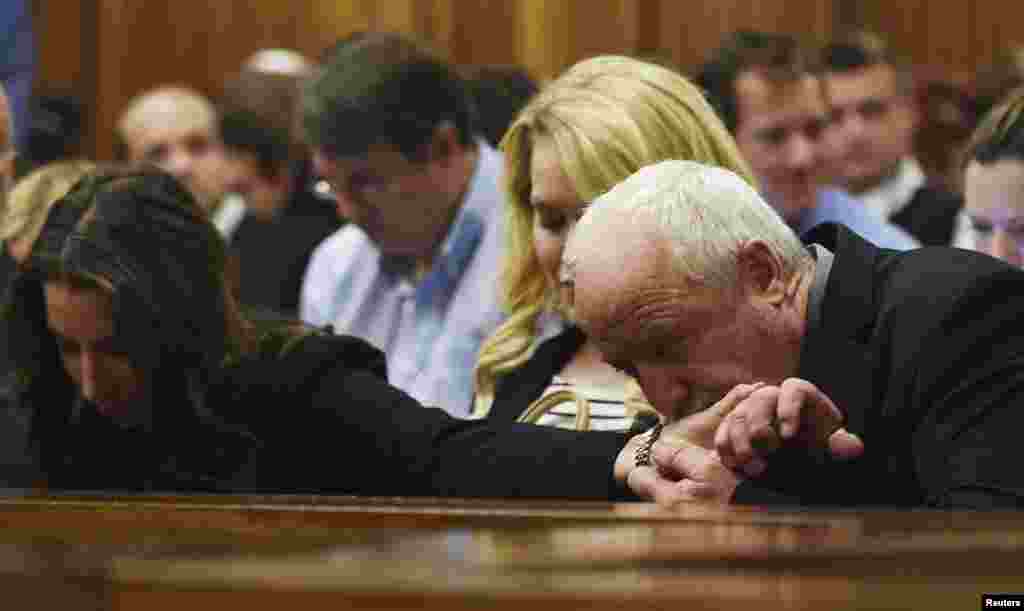 Henke Pistorius kisses the hand of his daughter Aimee Pistorius during the verdict for his son Oscar Pistorius at the North Gauteng High Court in Pretoria, Sept. 11, 2014. 