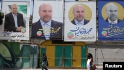 La gente pasa junto a pancartas del candidato presidencial Mohammad Bagher Ghalibaf exhibidas en una calle de Teherán, Irán, el 27 de junio de 2024. 