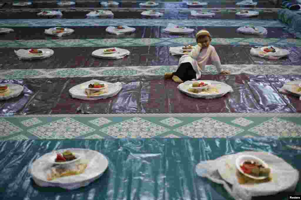 Seorang anak laki-laki menyaksikan orang-orang mendistribusikan makanan menjelang berbuka puasa di sebuah masjid di Singapura (29/6). (Reuters/Edgar Su)