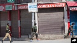 Polisi berlarian di dekat lokasi baku tembak di Sopore, 55 kilometer utara Srinagar, Kashmir yang dikuasai India, Sabtu, 12 Juni 2021. (AP/Mukhtar Khan)