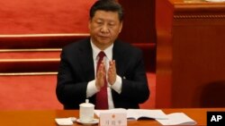 In this March 9, 2018 photo, Chinese President Xi Jinping claps to applaud China's Procurator-General Cao Jianming during a plenary session of China's National People's Congress at the Great Hall of the People in Beijing. 