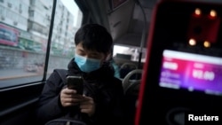 A passenger wearing a face mask checks his mobile phone on a bus, following an outbreak of the novel coronavirus in the country, in Beijing, China, Feb. 21, 2020.