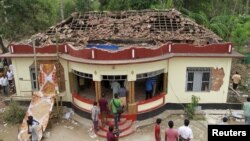 People gather around a damaged section of a temple after a fire broke out at a temple in Kollam in the southern state of Kerala, India, April 10, 2016. 