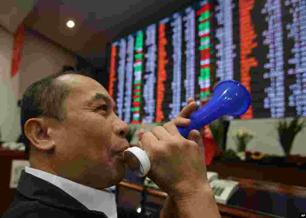 Seorang pekerja bursa saham Filipina meniup terompetnya di depan papan elektronik bursa pada hari terakhir perdagangan bursa tahun ini di Bursa Saham Filipina di distrik keuangan Makati, Manila selatan. Indeks bursa asing naik ke rekor tinggi mencapai 7,403.65.