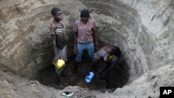 In this photo taken March 22, 2019, Kenyan children dig deep into a dry river bed to retrieve water in Tarach, Turkana county, in northern Kenya.