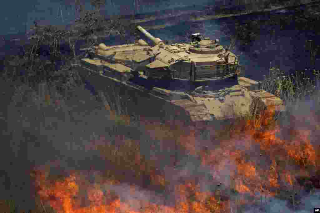 Sebuah tank militer tua dikelilingi api pasca ledakan mortir di wilayah dataran tinggi Golan yang dikuasai Israel.