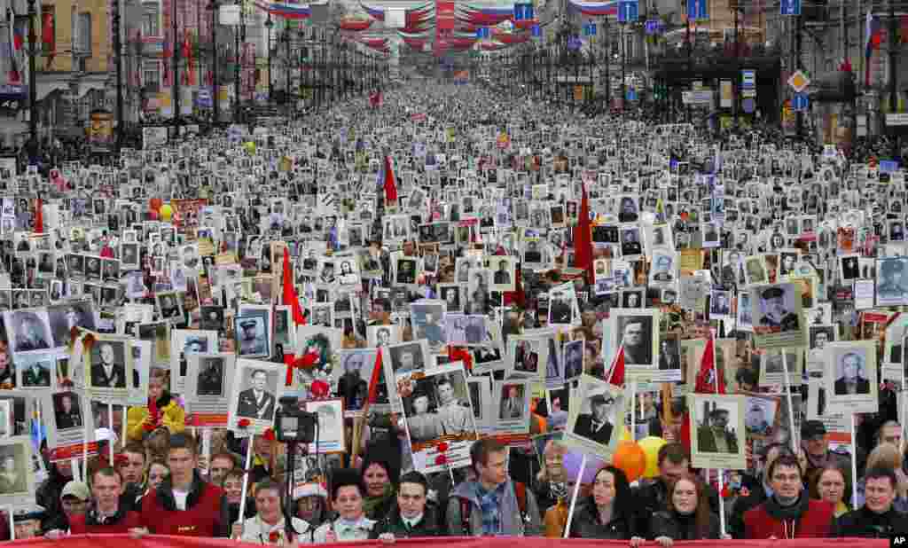 Warga setempat membawa potret para leluhur mereka yang ikut dalam Perang Dunia II, dalam merayakan Hari Kemenangan di St. Petersburg, Rusia. Sekitar 30.000 orang berbaris dalam parade "Resimen Abadi" Hari Kemenangan, yang menandai kekalahan Nazi Jerman. Peringatan tersebut adalah perayaan sekuler paling penting di Rusia. 