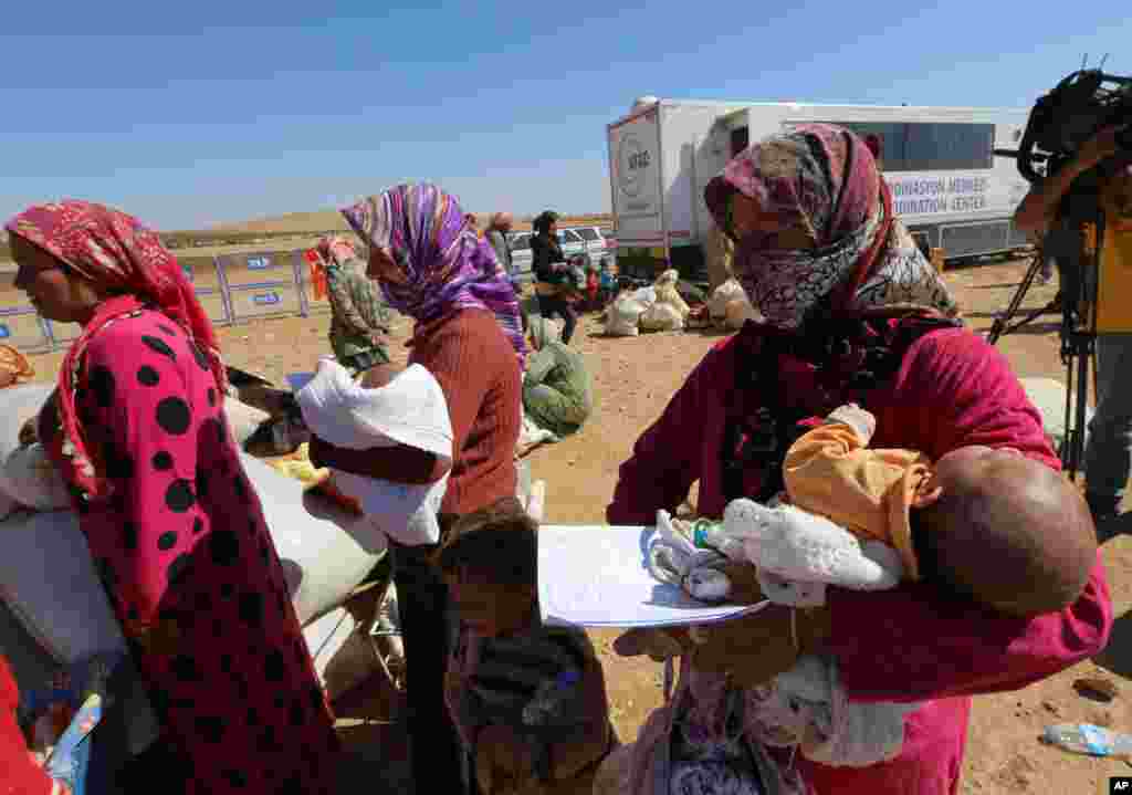 Narin Mustafa, 26 (center) holds her 10-day-old baby girl as thousands of new Syrian refugees from Kobani arrive at the Turkey-Syria border crossing of Yumurtalik near Suruc, Turkey, Oct. 1, 2014.