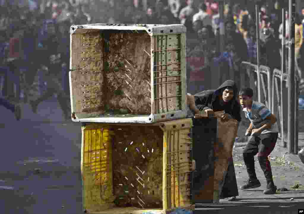 Palestinians take cover during clashes with Israeli soldiers following a rally marking the 9th anniversary of late Palestinian leader Yasser Arafat's death, in the West Bank city of Hebron.