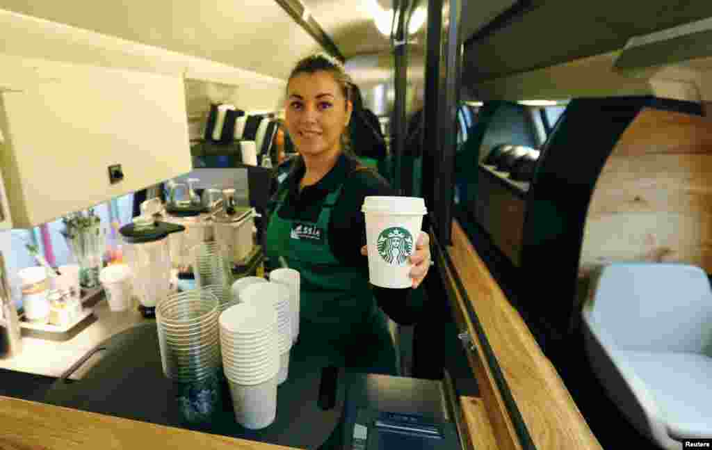 Seorang karyawati Starbucks memerlihatkan kopi Starbucks di kedai Starbucks yang baru di dalam kereta api Swiss SBB di Zurich. Starbucks, jaringan gerai kopi terbesar di dunia menghadirkan kedai bertingkat dua yang pertama di kereta api antarkota SBB dengan rute perjalanan antara kota Swiss St. Gallen dan Jenewa, 14 November 2013.
