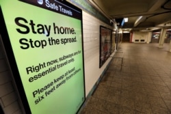 FILE - A message is seen on an electronic display inside a mostly empty 42nd Street subway station during the coronavirus outbreak in New York City, March 20, 2020.